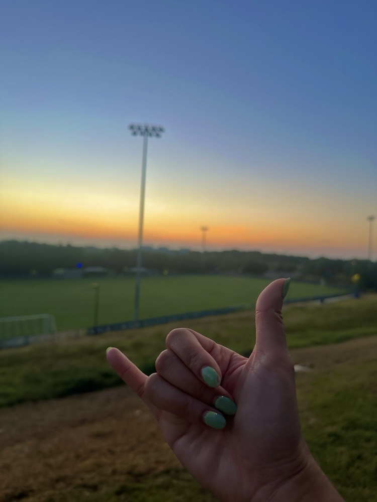 A shaka at sunset over the field in Austin